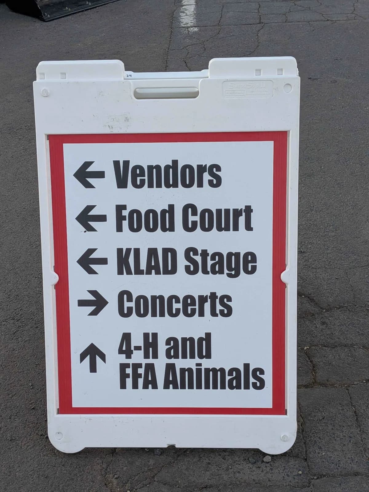Klamath County Fair direction sign pointing visitors toward vendors, food court, stage, concerts, 4-H, and FFA animals